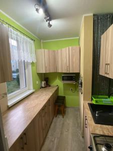 eine Küche mit grünen Wänden, Holzschränken und einem Fenster in der Unterkunft Sunset Studio in Danzig