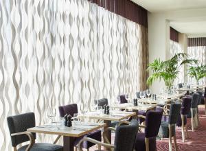 a row of tables and chairs in a room with a wall at Leonardo Hotel Bradford in Bradford