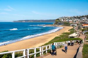 un gruppo di persone che camminano lungo la spiaggia di Townhouse on The Hill a Newcastle