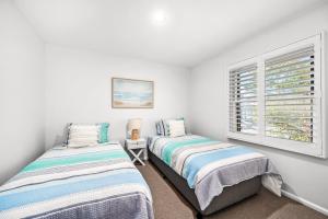 two beds in a white room with a window at Townhouse on The Hill in Newcastle