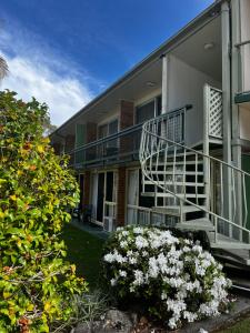 a building with a staircase and flowers in a yard at Motel Miramar in Nambucca Heads