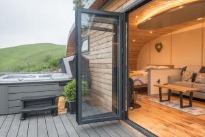 a tiny house with a hot tub and a bedroom at Fern - Beacon View Pods in Knighton