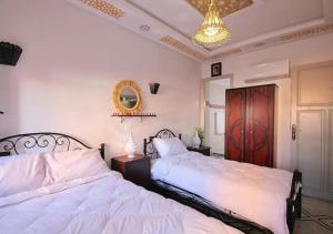 a bedroom with two beds and a chandelier at Araf House in Marrakesh