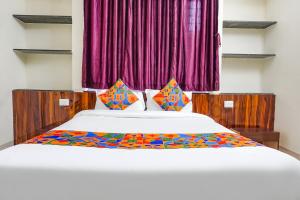 a bedroom with a large white bed with colorful sheets at FabHotel Stay Inn - IT Hub in Pune