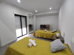 アルマカオ・デ・ペラにある8-2 Torre Sol - Casas & Papéisの黄色いシーツが備わる客室内のベッド2台