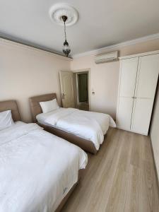 Duas camas num quarto com paredes brancas e pisos em madeira em Esa Suite Hotel em Trabzon