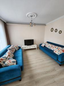 sala de estar con 2 sofás azules y TV en Esa Suite Hotel en Trabzon