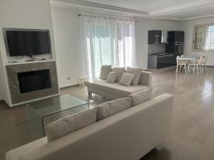 a white living room with a couch and a tv at Villa Rachele con piscina in Balestrate