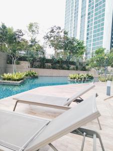 una piscina con 2 mesas blancas y edificios en Greenfield Residence Bandar Sunway Petaling Jaya en Petaling Jaya