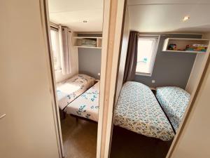 Cette petite chambre comprend 2 lits et un miroir. dans l'établissement Mobilhome P27 6 personnes climatisé, à Le Portel