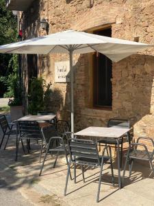 een groep tafels en stoelen met een paraplu bij Hostal de Bianya in Vall de Bianya