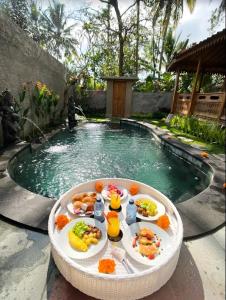 ウブドにあるD'Ethnic Ubud Joglo View Villas by EPSのプール前のテーブルにトレイ