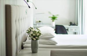 a vase of flowers sitting on a table next to a bed at Hotel Aqua Sopot - Destigo Hotels in Sopot
