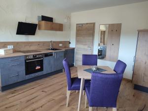 a kitchen with a wooden table and purple chairs at Bergkristall MeineCard Plus in Willingen