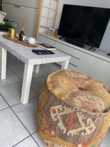 sala de estar con mesa, TV y taburete en Gezellig en knus app vlakbij centrum Nieuwpoort!, en Nieuwpoort