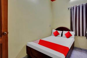 Schlafzimmer mit einem Bett mit roten und weißen Kissen in der Unterkunft OYO Flagship 81231 Urmila Guest House in Bodh Gaya