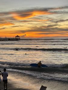 um grupo de pessoas de pé na praia ao pôr do sol em Totora Surf Hostel em Huanchaco