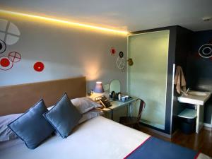 una camera da letto con letto con cuscini blu e scrivania di Bannister Hotel a Johannesburg