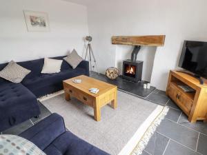 a living room with a blue couch and a fireplace at Bronyrhiw in Goodwick