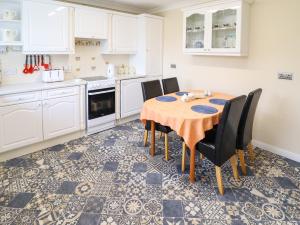 a kitchen with a table and chairs and white cabinets at Joray Bungalow in Alford