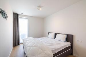 - une chambre avec un lit doté de draps blancs et une fenêtre dans l'établissement VivaVela, à Nieuport