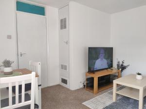 a living room with a television and a table at Spacious Comfortable 4 bedroom house in Aylesbury