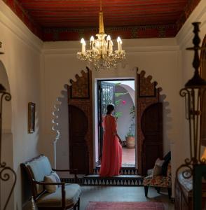 a woman in a red dress looking in a mirror at Lalla Ghayta in Chefchaouene