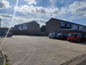a parking lot with cars parked in front of a building at Spacious Comfortable 4 Bedroom House in Aylesbury