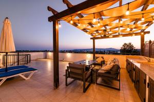 un patio con pérgola, mesa y sillas en Blue Serenity Complex, en Lárnaca