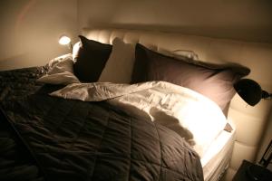 1 cama con almohadas blancas y negras y lámpara en Spacious & refurbished 1 bedroom apartment in suburban Reykjavik, en Garðabær