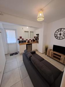 a living room with a couch and a clock on the wall at Logement Cosy T2, Centre ville de Saint-Pierre in Saint-Pierre