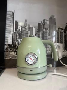 a green tea kettle with a clock on a table at Уютная и комфортная 3х комнатная в новом центре in Uralsk