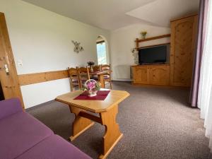 sala de estar con mesa y TV en Pension Roasthof, en Neustift im Stubaital