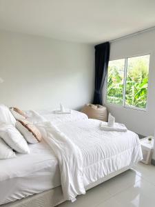 a white bedroom with a white bed and a window at BAOBAB in Patong Beach