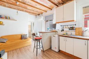 una cocina con armarios blancos y un sofá en una habitación en Beachside Bliss Charming 1-bedroom, Barceloneta, en Barcelona