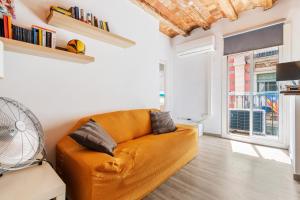 un sofá naranja en una sala de estar con ventana en Beachside Bliss Charming 1-bedroom, Barceloneta, en Barcelona