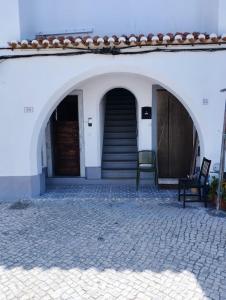 ein weißes Gebäude mit zwei Bögen und einer Treppe in der Unterkunft Katyto house in Costa da Caparica