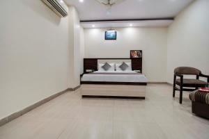 een slaapkamer met een bed en een stoel bij Capital O Hotel Pink Peral in Jaipur