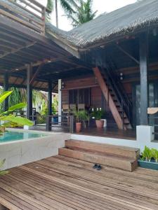 une maison avec une terrasse en bois et une piscine dans l'établissement Halekahakai, à Talisay