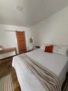 um quarto com uma grande cama branca e uma porta de madeira em Jardim Tropical em Lauro de Freitas