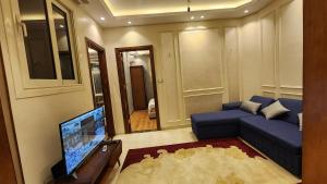 a living room with a blue couch and a tv at Azarita luxury apartment - families only in Alexandria