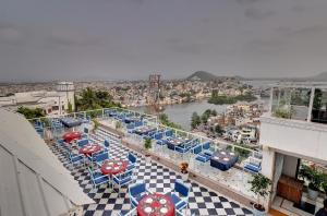 a balcony with tables and chairs and a view of a city at Hotel Darbargarh A Unit of Khamma Ghani A Boutique Hotel in Udaipur
