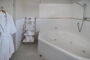 Baño blanco con bañera y toallero en Whangaparaoa Lodge en Whangaparaoa