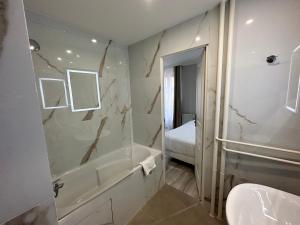 ein Badezimmer mit einer Badewanne, einem WC und einem Waschbecken in der Unterkunft Hotel Riviera Renovated in Paris