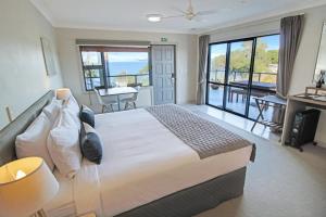 1 dormitorio con 1 cama grande y balcón en Whangaparaoa Lodge, en Whangaparaoa