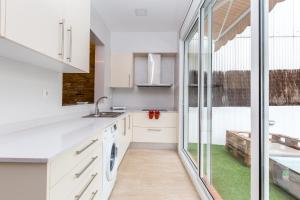 eine Küche mit weißen Schränken und einem Waschbecken in der Unterkunft Grcia Charm Sunlit Terrace, Ac & Exposed Brick in Barcelona