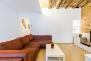 ein Wohnzimmer mit einem braunen Sofa und einem weißen Tisch in der Unterkunft Grcia Charm Sunlit Terrace, Ac & Exposed Brick in Barcelona