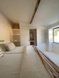a white bedroom with a large white bed with a window at Casa Buganvilla in Alcácer do Sal