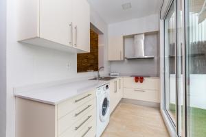 eine Küche mit weißen Schränken, einer Waschmaschine und einem Trockner in der Unterkunft Grcia Charm Sunlit Terrace, Ac & Exposed Brick in Barcelona