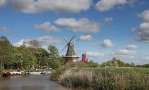 eine Windmühle an der Seite eines Flusses mit Booten in der Unterkunft Heimathafen Sillenstede in Schortens